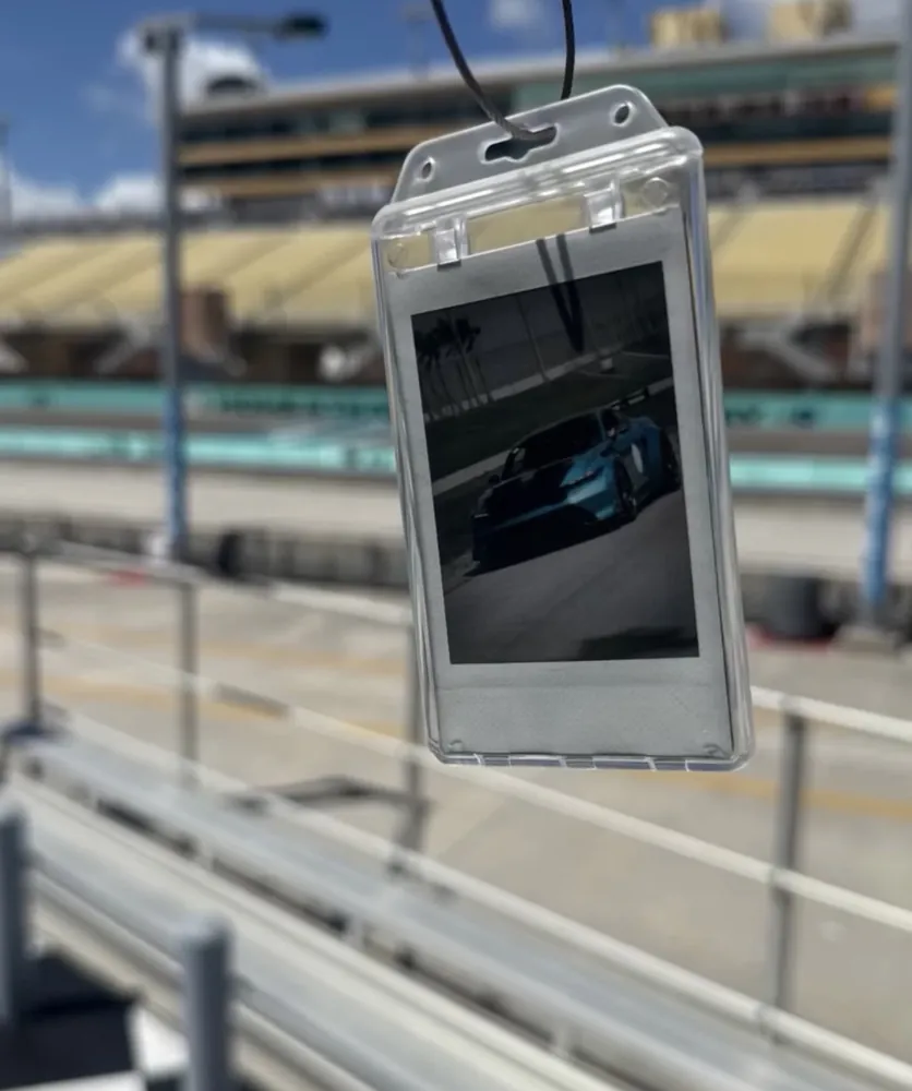 A custom Frame Wave tag with a race car photo, held at a racetrack
