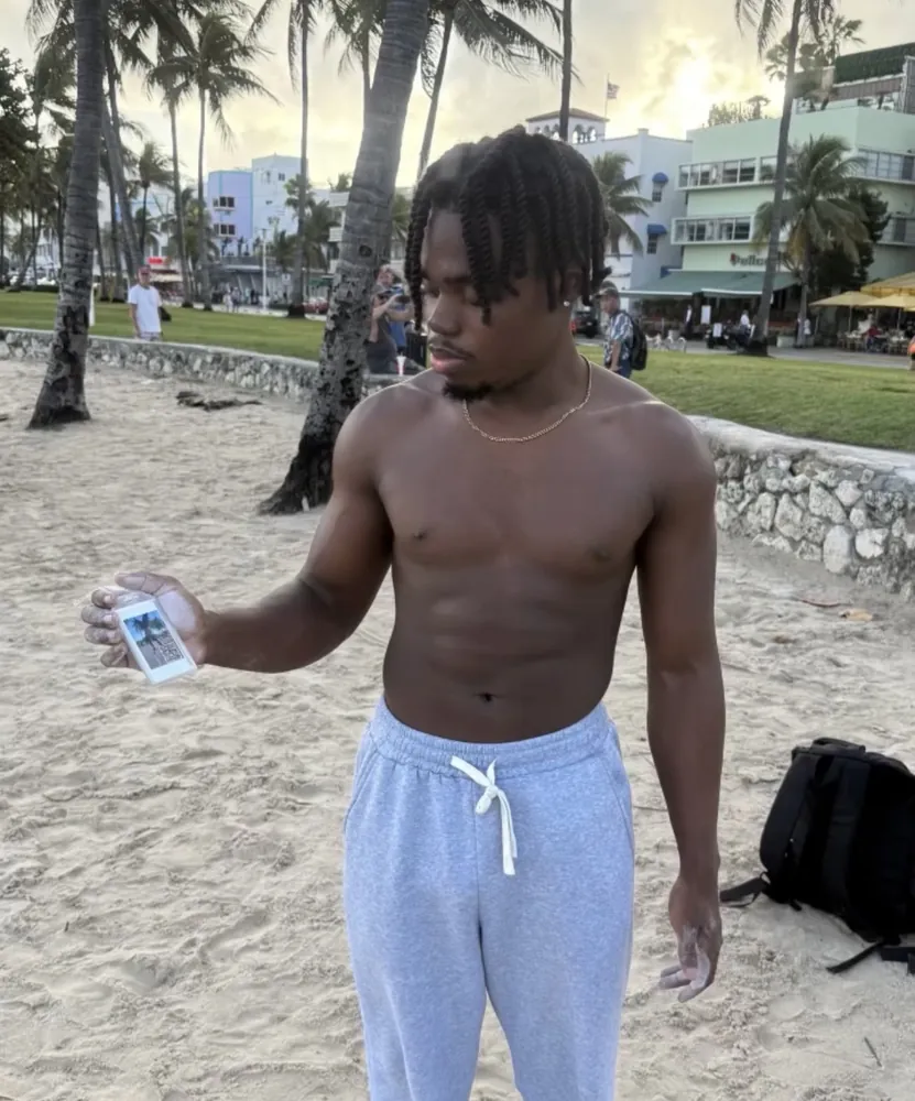 A customer holding a custom Frame Wave tag at the beach